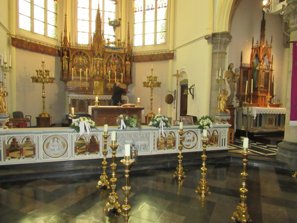 Uitvaartdienst voor Fons Castermans in de Sint-Petrus-en-Pauluskerk in Wolder (Maastricht) op 8 april 2022. Achter de voorste rechterkaars staan 2 foto’s van Fons Castermans, op de linkerfoto staat hij met zijn vrouw Riet Castermans-Janssen, op de rechterfoto houdt hij glunderend abondance 12 (bij whisten 12 van de 13 slagen) in zijn hand.